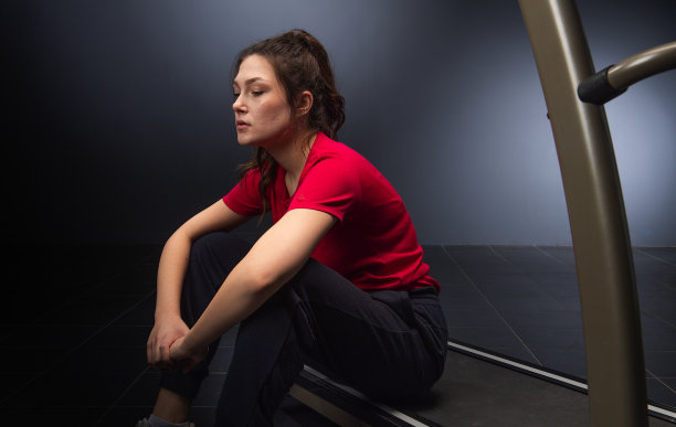 疲惫的年轻女孩坐在健身房图片下载