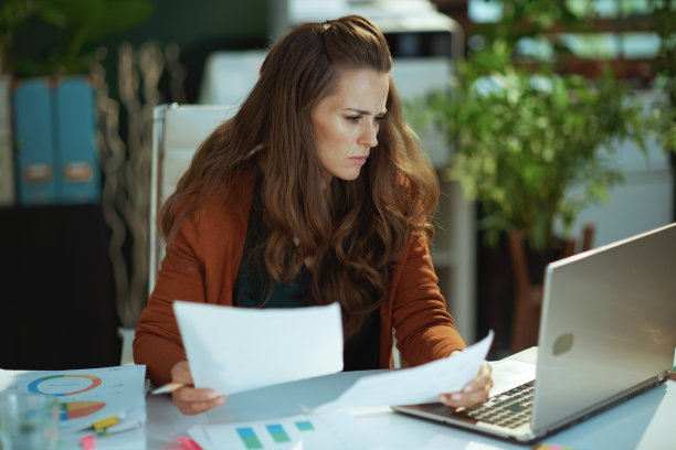 在绿色办公室里处理文件的女老板图片下载