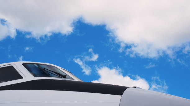 带有黑色条纹的白色飞机的机头。飞行员的座舱。镜头从右向左移动，显示出一架白色飞机的机头。客机在机场。图片下载