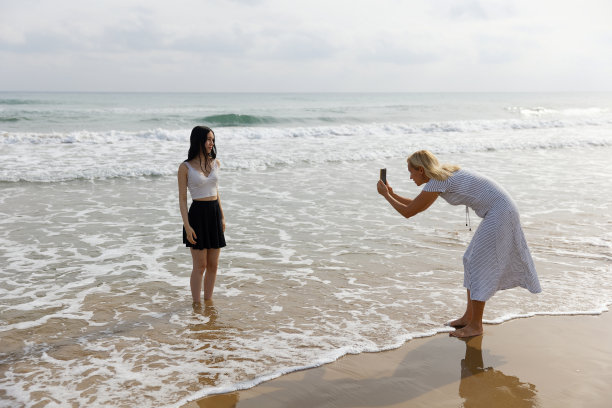 一位母亲在海上用手机给女儿拍照图片下载