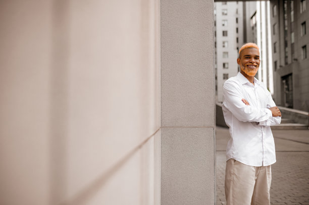 一张以城市为背景的深色皮肤、穿着白色衣服的高个子男人的照片图片下载