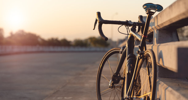 公路自行车停在美丽的马路上夕阳西下，在桥上温暖的灯光下复制空间。图片下载
