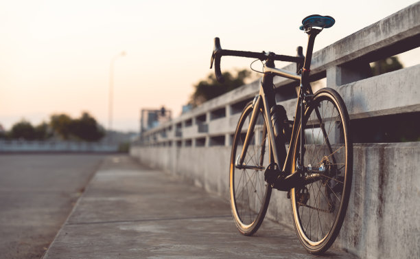 公路自行车停在美丽的马路上夕阳西下，在桥上温暖的灯光下复制空间。图片下载
