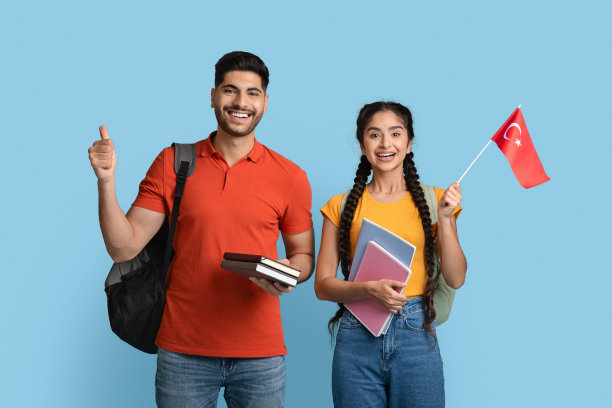 在土耳其学习。快乐的阿拉伯学生夫妇与练习册持有土耳其国旗图片下载