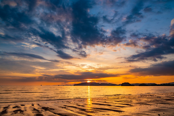 美丽的日落与戏剧性的云和天空的蓝色和橙色。泰国甲米镇的Ao Nang海滩。图片下载