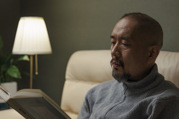 中年男子在沙发上看书图片下载