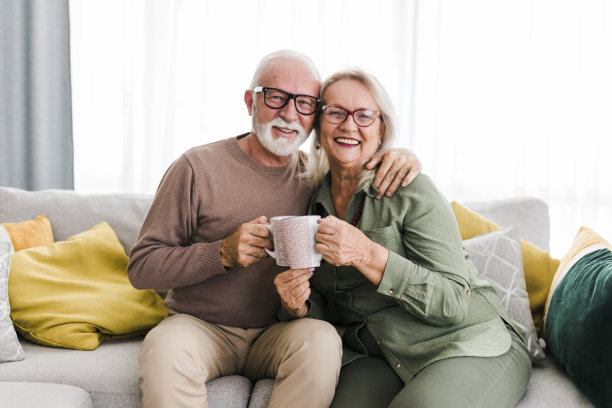 老两口退休老两口在家里的沙发上喝着茶，谈笑风生，喜气洋洋图片下载