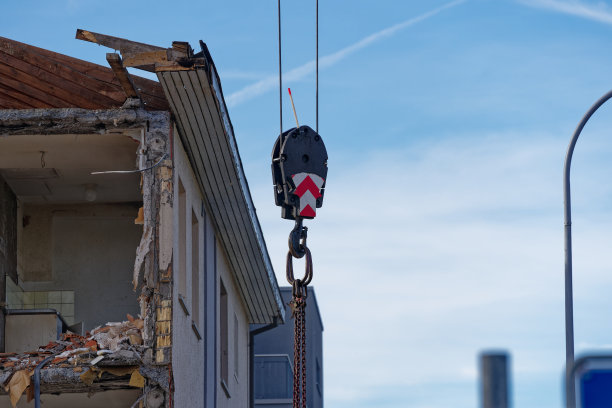 在一个阳光明媚的秋日，用钩子拿着黑色防尘帆布拆除公寓楼的解构现场。图片下载