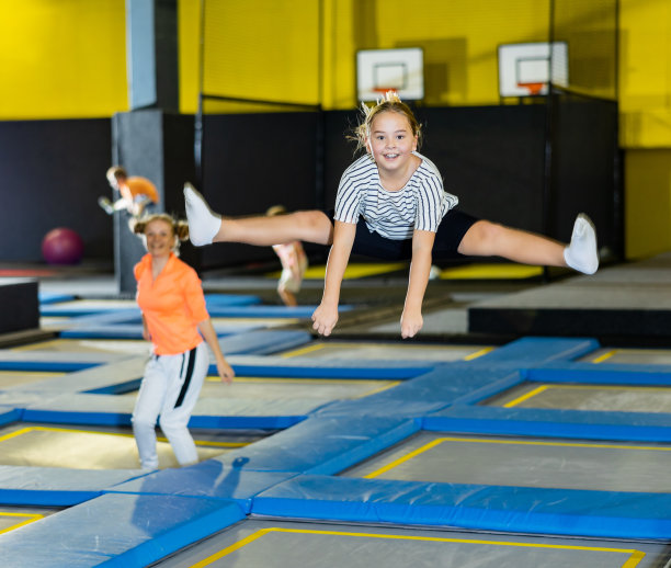 周末空闲时间，在娱乐中心蹦床上伸展双腿的快乐女孩图片下载
