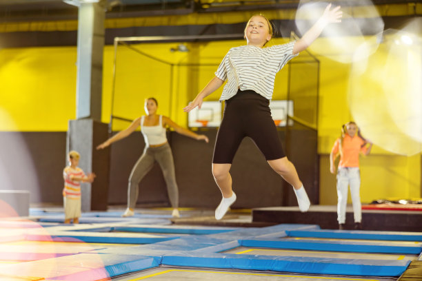 女孩在运动中心蹦床公园跳跃图片下载