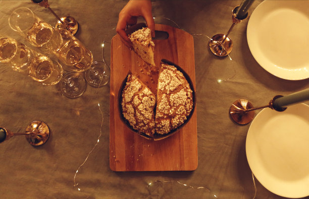 女性拿着一片新烤的潘妮托妮蛋糕在餐桌上为节日晚餐，照片在乡村风格图片下载