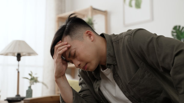 特写照片中，一名压力巨大的亚洲年轻男性呆在家里，对封锁期间的经济问题感到非常焦虑，绝望地撑着头。图片下载