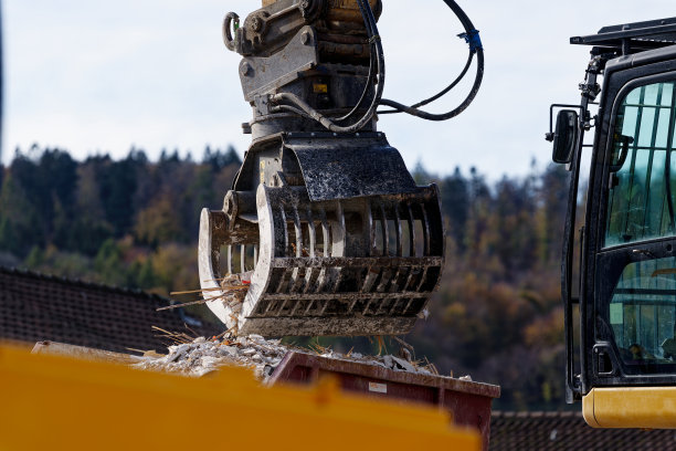在一个阳光明媚的秋日，挖掘机用黑爪拆除了一座带有木质屋顶框架的公寓楼。图片下载