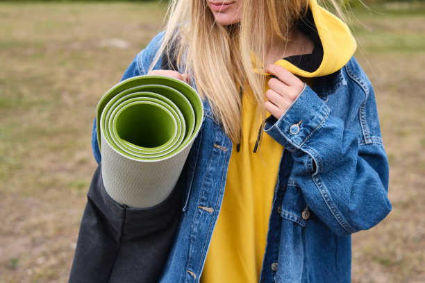 一个爱运动的女孩正拿着运动垫在大自然中准备瑜伽。户外健身瑜伽。健康与运动概念图片下载