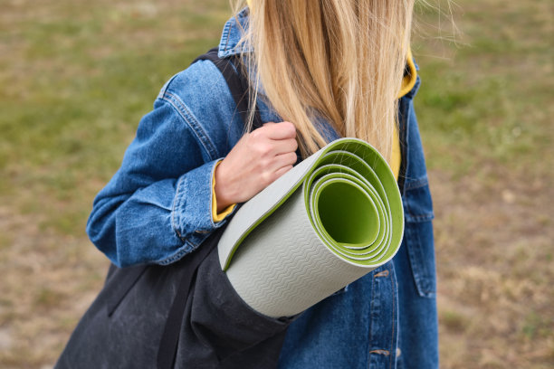 一个爱运动的女孩正拿着运动垫在大自然中准备瑜伽。户外健身瑜伽。健康与运动概念图片下载