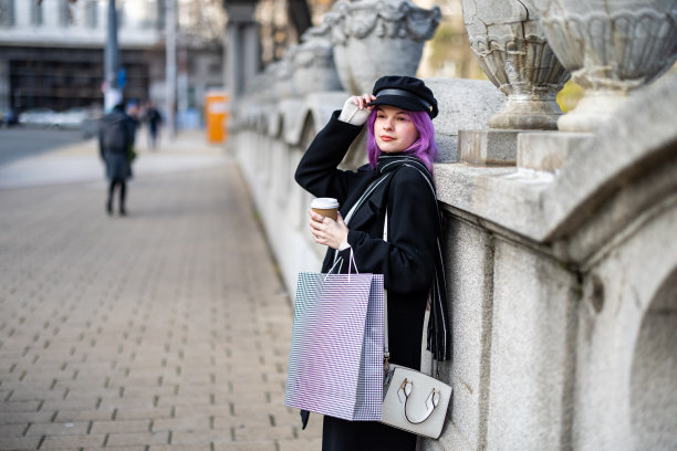年轻女子在城市街道上喝咖啡的肖像。图片下载