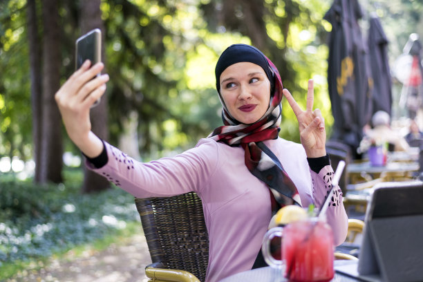 一名穆斯林女子一边喝果汁一边自拍。图片下载