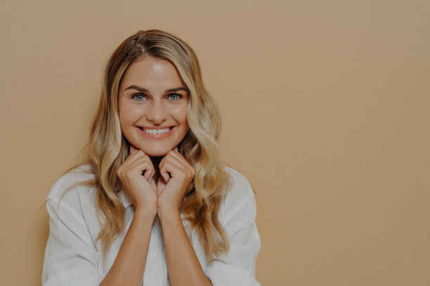 年轻的金发女性保持双手折叠在下巴下，狡猾地看着相机图片下载