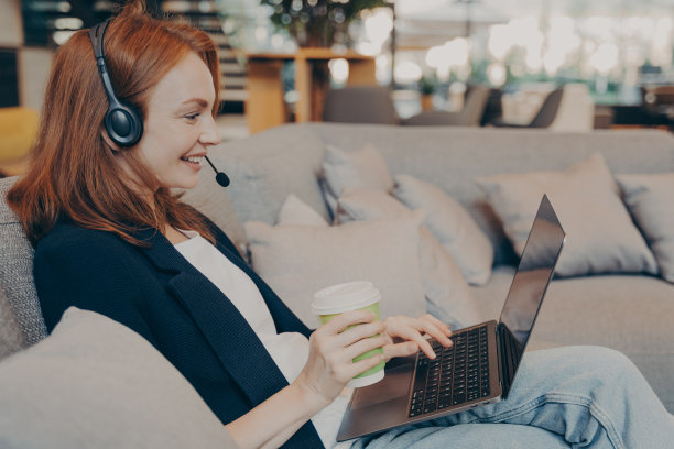 年轻的女教师带着无线耳机和笔记本电脑在咖啡厅举行视频会议图片下载