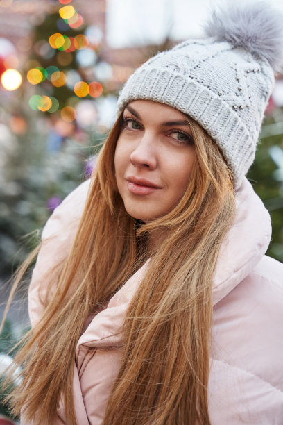一个美丽的年轻女子的肖像在圣诞树外面的彩灯前图片下载