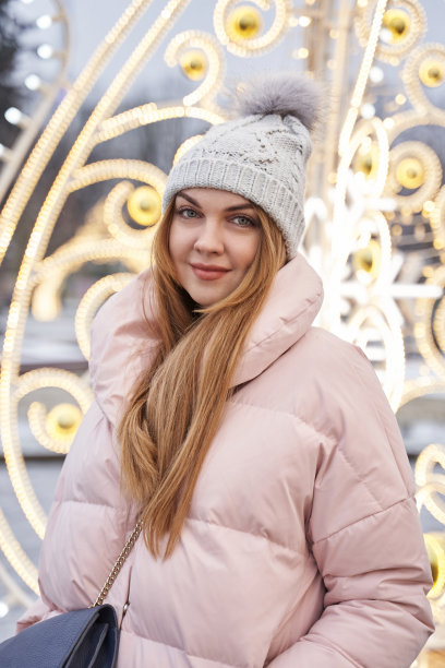 这是一幅冬日里的年轻女子的肖像，背景是一座装饰华丽的圣诞城市的彩灯。新年心情图片下载