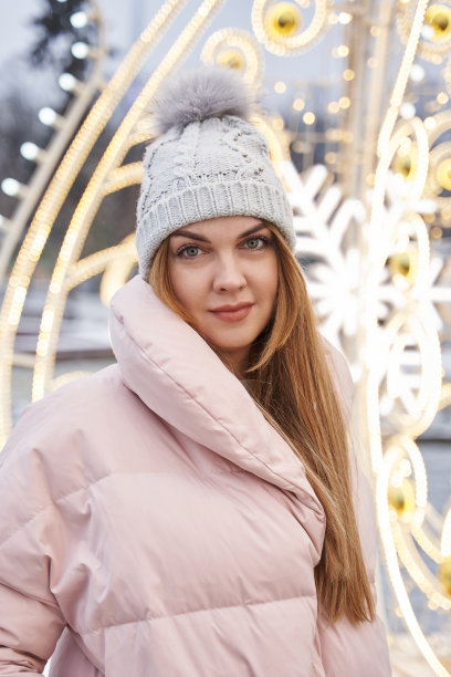 美丽的年轻女子，穿着暖和的冬装，留着长发。背景圣诞市场的灯光图片下载