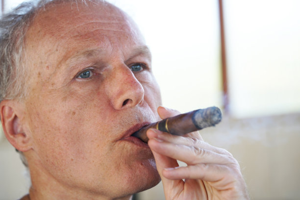 一个美丽的女人的肖像慢慢释放烟雾从她的嘴，而雪茄是在她的右手。图片下载