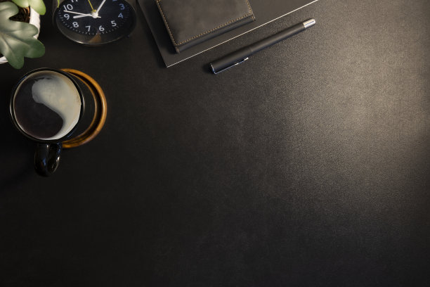 俯视图的黑色办公桌与笔记本，钢笔，盆栽和咖啡杯。复制文本空间。图片下载