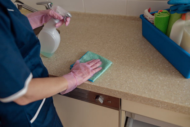 戴着防护手套的女佣在厨房用抹布和有效的洗涤剂清洁工作台面图片下载