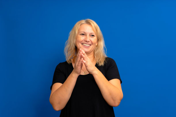 期待着一个美丽的白人女人摩拳擦掌的好主意。她站在有复制空间的蓝色背景上。有趣的报价或销售概念图片下载