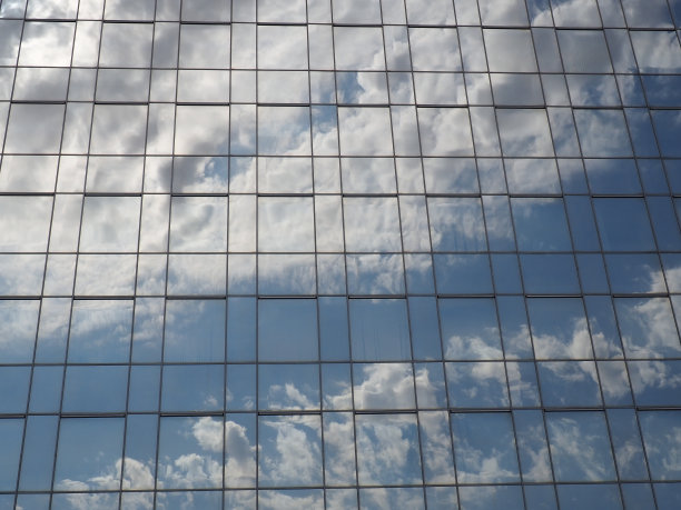 天空和建筑的玻璃立面。蓝天白云映照在玻璃墙上。城市摩天大楼。现代玻璃建筑和建筑。生态学的概念图片下载