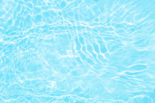 离焦模糊透明蓝色颜色清晰平静的水面纹理与飞溅和气泡。潮流抽象的自然背景。水波在阳光下带有焦散。碧水浪花闪闪发光图片下载
