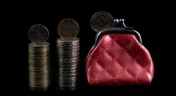 面值为50、100和200坚戈的哈萨克硬币和一个黑色背景的红色钱包银行图片下载