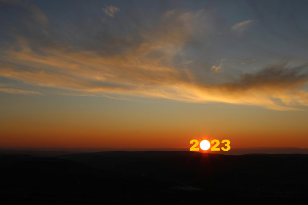 2023年新年快乐。从2022年过渡到2023年的概念，文本是太阳升起的天空。图片下载