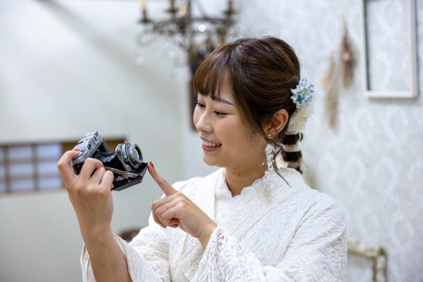 身穿白色蕾丝和服的女子手持老式相机图片下载