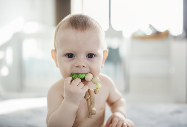 可爱的男婴玩一个木制的出牙玩具。图片下载
