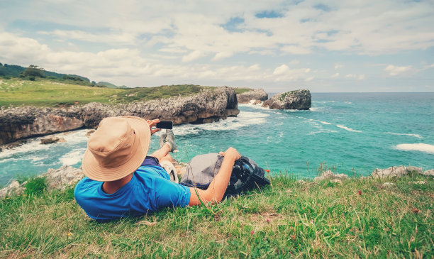 背包客在岩石海边休息，拍摄美丽的海景照片图片下载