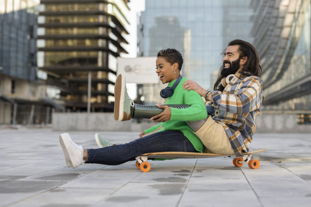 不同的夫妇一起玩户外滑板在城市图片下载