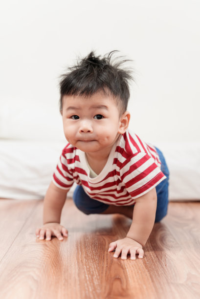 可爱的亚洲男婴在地板上爬行，微笑着看着镜头。图片下载