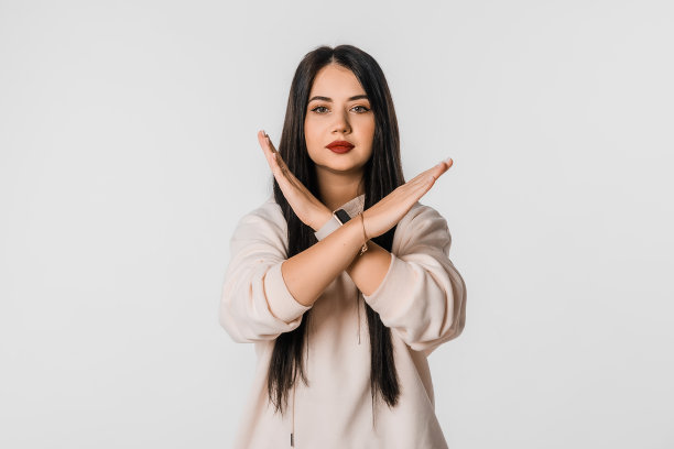 肖像黑发年轻女子双手交叉愤怒的情绪，站在白色的工作室背景。严肃的学生女孩拒绝某件事图片下载