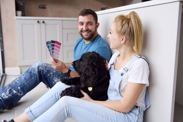 夫妇在家中厨房装修时休息喝咖啡，宠物西班牙猎犬在旁图片下载