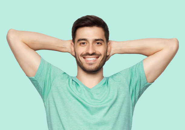 一个年轻人站在那里，双臂放在脑后，悠闲地放松着图片下载