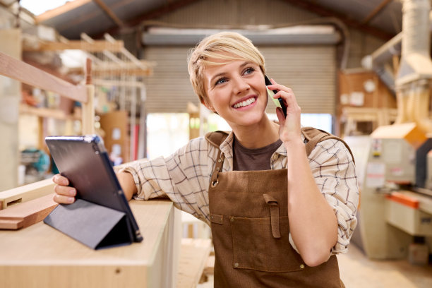 女学徒拿着平板电脑在家具车间当木匠打电话图片下载