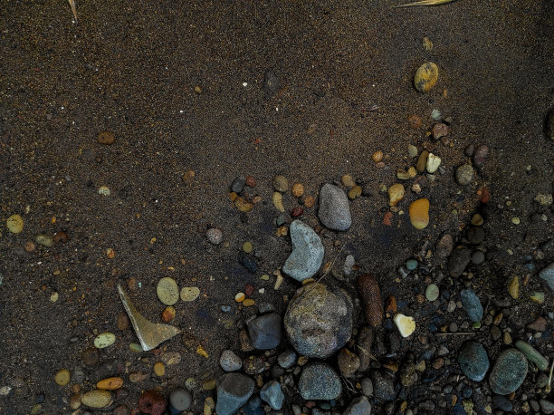 黑色的沙子和一些石头在同一土地的纹理图片下载