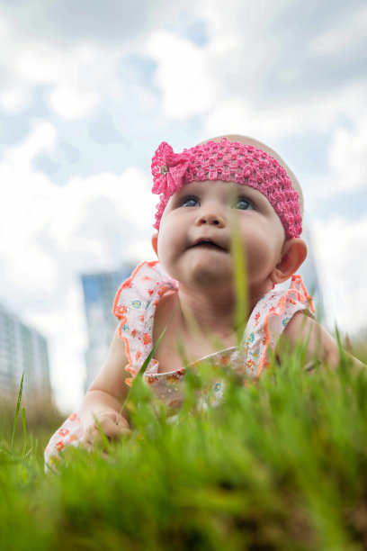 有趣的女婴爬在绿色草坪夏季城市公园，好奇的兴趣。可爱的孩子在春天散步时玩得很开心。快乐童年与宝宝保健理念。本空间图片下载