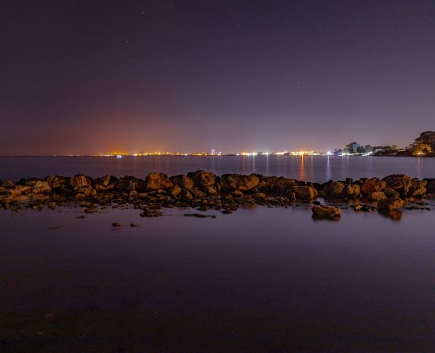 风景如画的城市灯光倒映在水中，照片摄于海滩图片下载