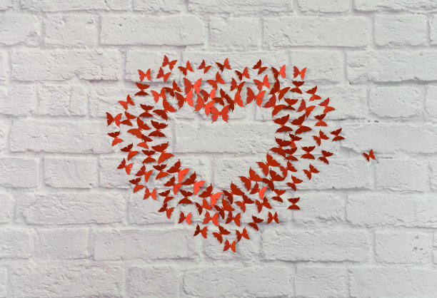 砖墙背景上的蝴蝶心。爱的概念。图片下载