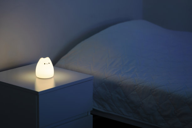 可爱的猫形夜灯放在床边的床头柜上。图片下载