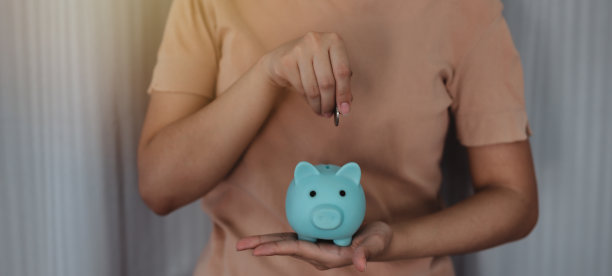 年轻女子手里拿着保护储蓄罐和计划不断增长的储蓄，为未来的旅行、教育、家庭和退休计划提供一堆硬币。图片下载