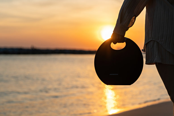 女子在日落背景上持有扬声器。概念是快乐的。图片下载